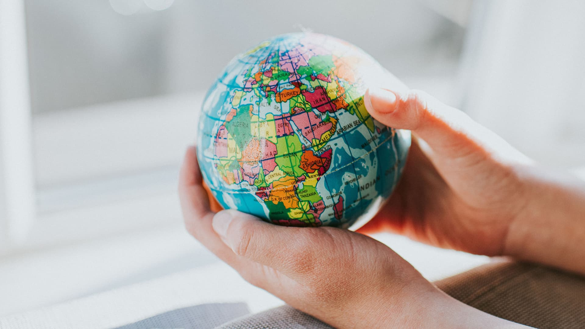 Hände halten Globus am Fenster. Africa, Asien und Europa sind zu sehen.