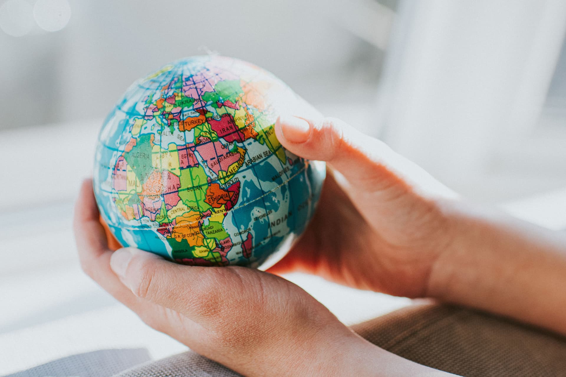 Hände halten Globus am Fenster. Africa, Asien und Europa sind zu sehen.