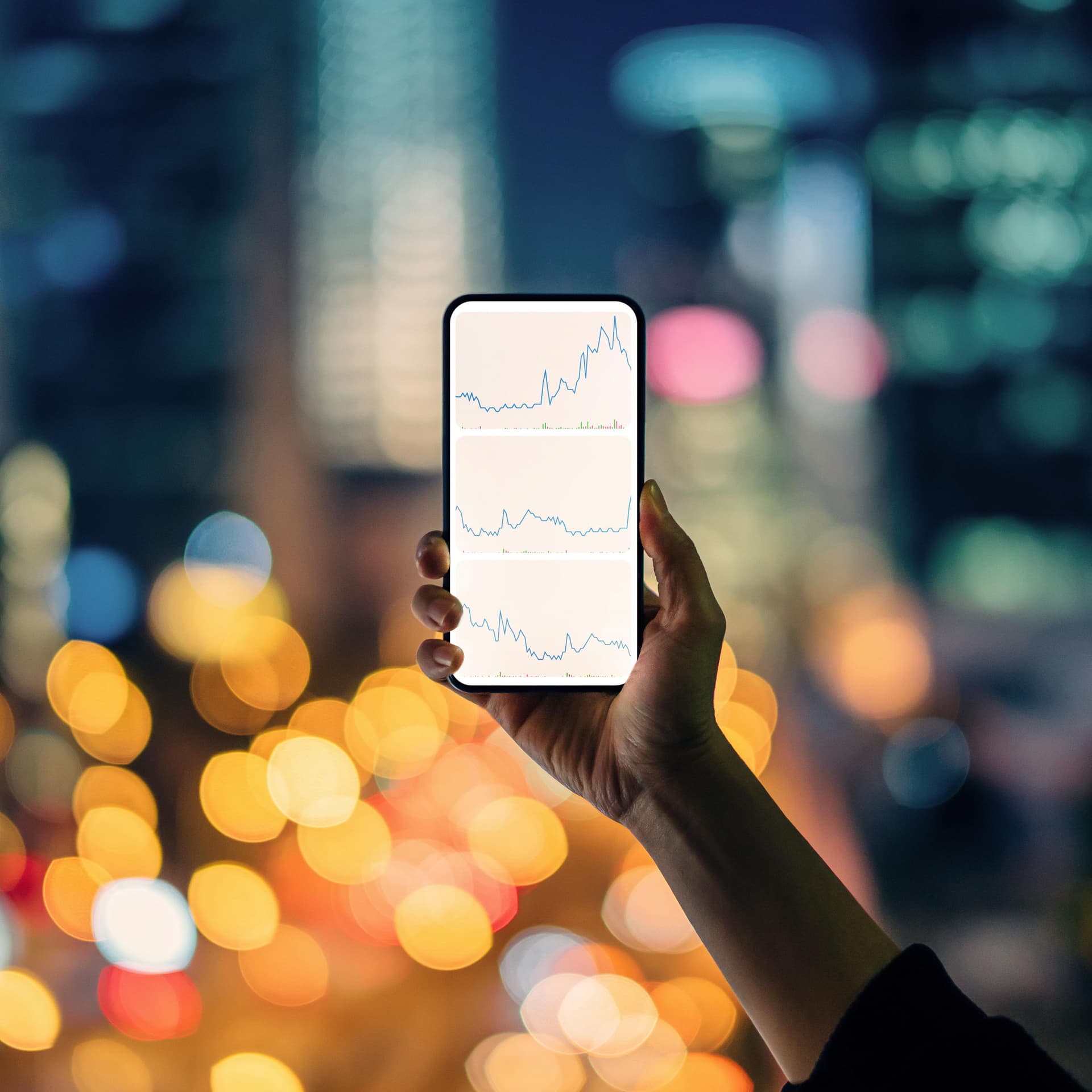 Person hält ein Smartphone mit Datenkurven auf dem Display in der Hand. 