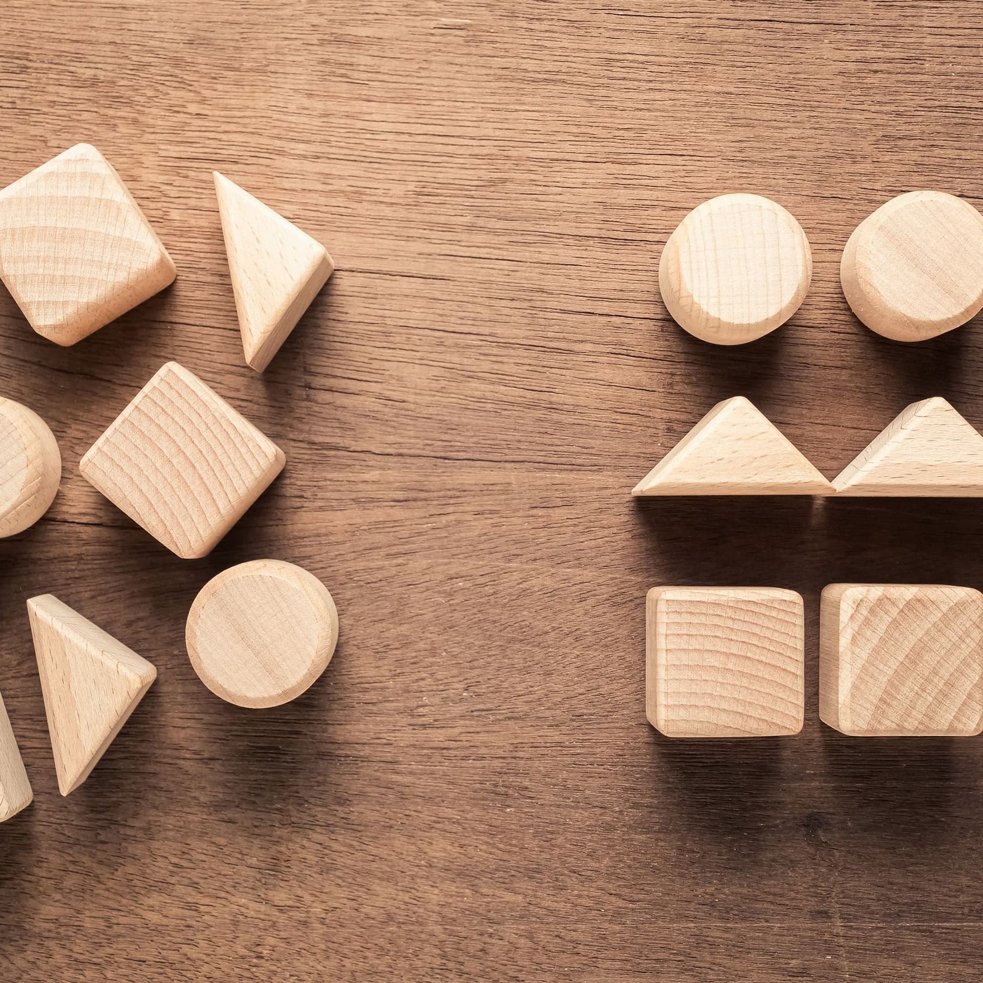 Auf einem Holztisch liegen sortierte und unsortierte Holzklötze in verschiedene geometrischen Formen.