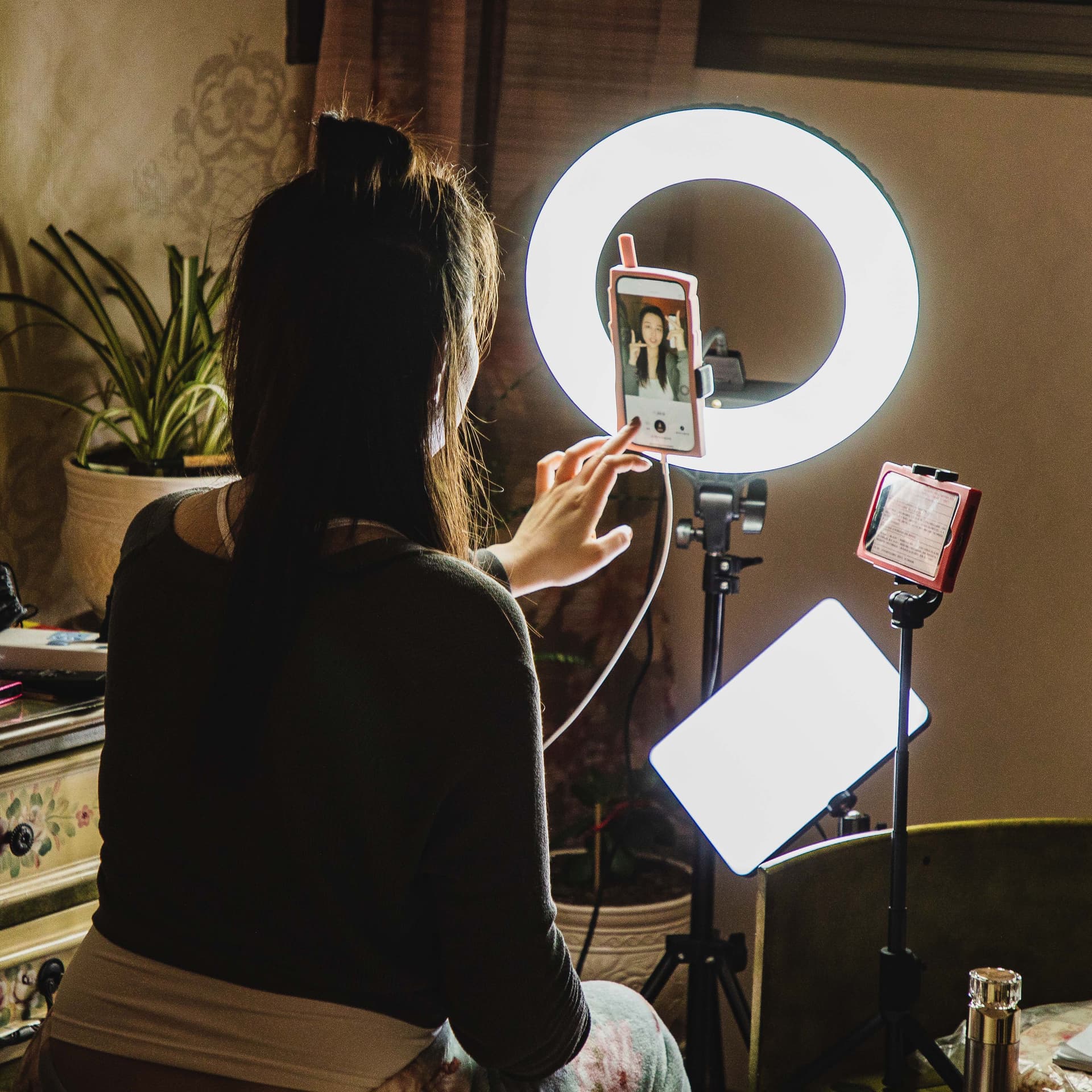 Eine Influencerin sitzt vor ihrem Smartphone mit Beleuchtung.
