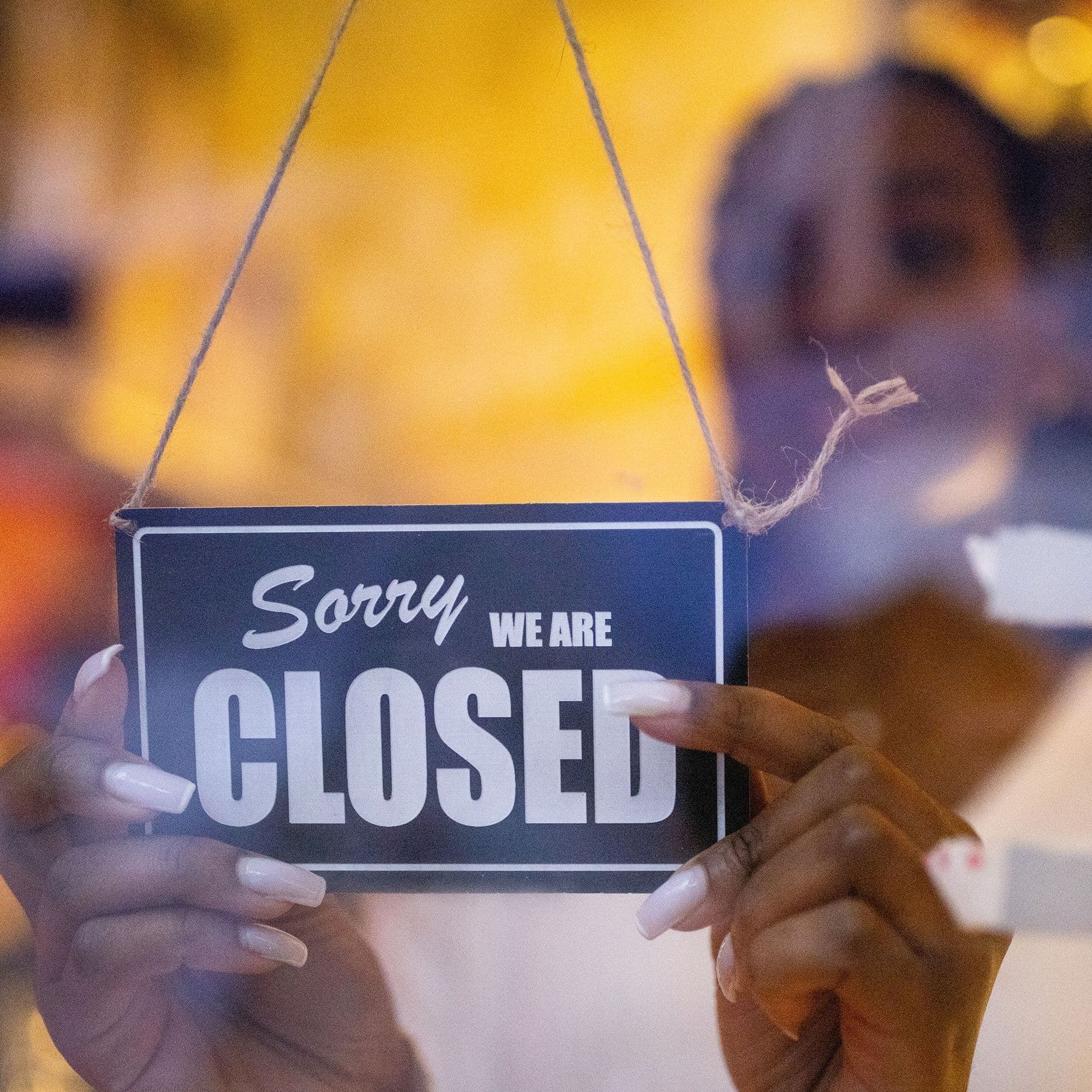 Eine Frau dreht ein "Sorry, we are closed"-Schild um.
