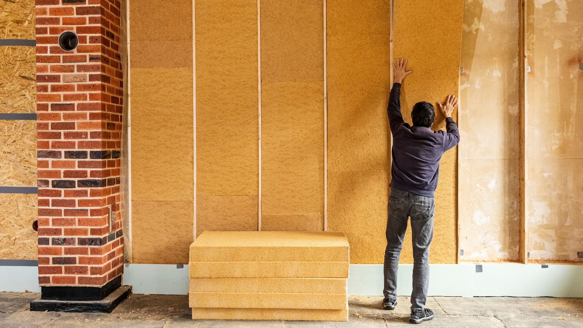 Ein Mann baut eine Wärmedämmung in eine Wand ein.