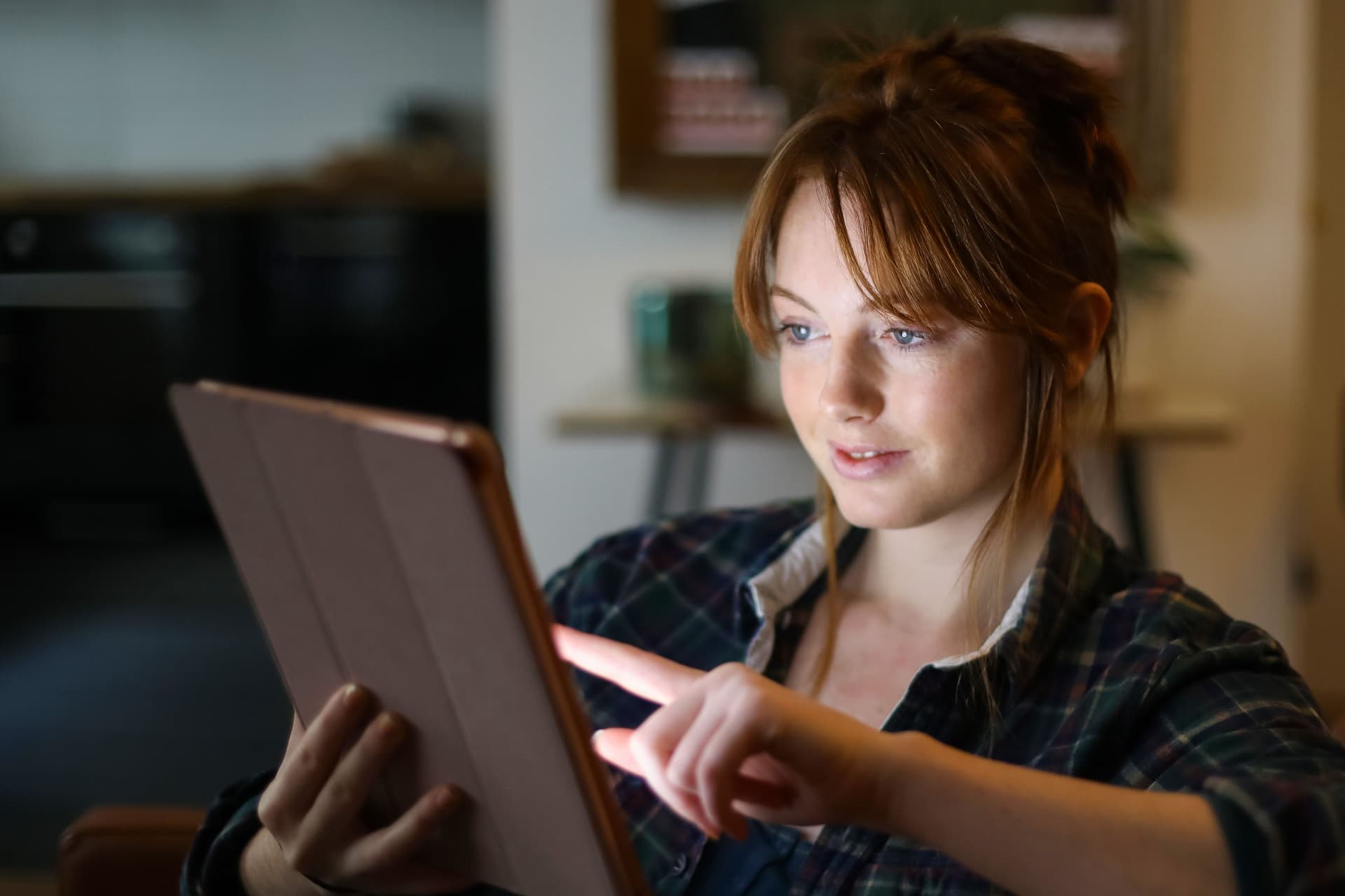 A young woman looking at a digital tablet at home