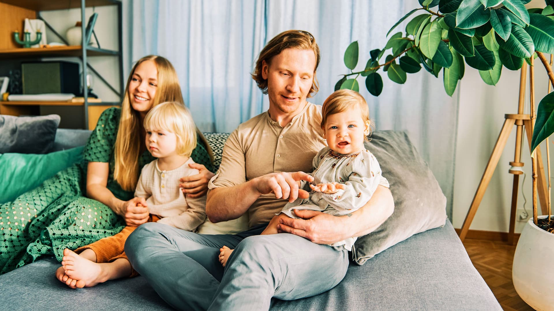 Mann und Frau mit zwei Kindern sitzen auf einem Sofa. 