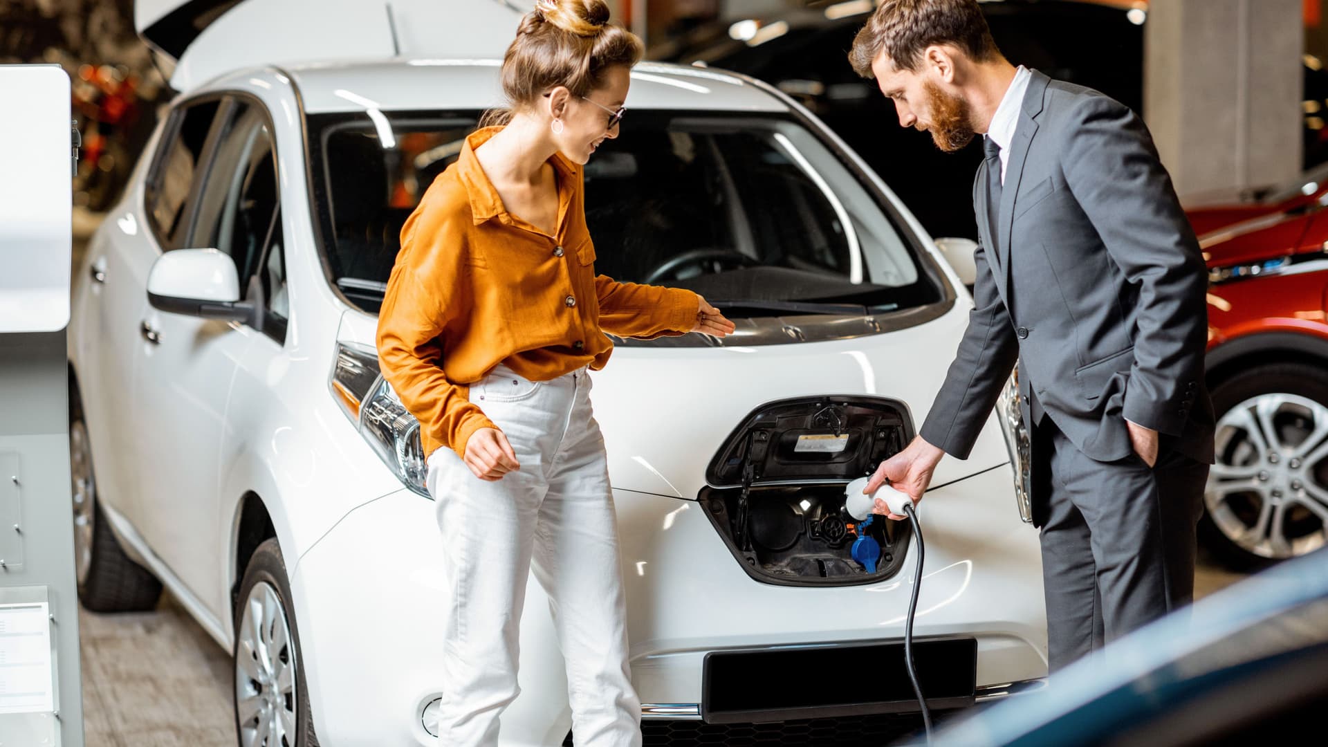 Ein Autoverkäufer zeigt einer Kundin ein Elektroauto.