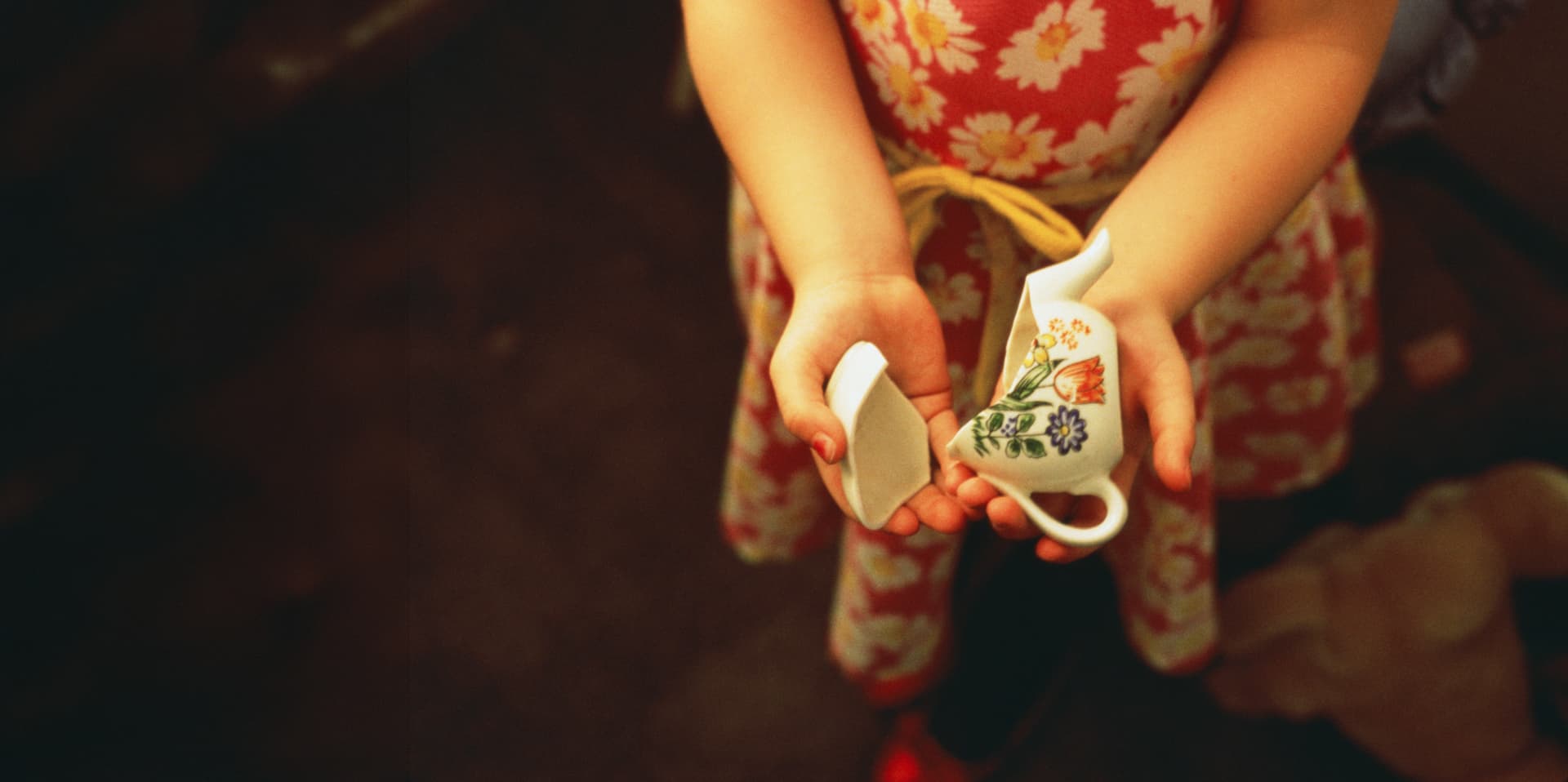 Kinderhände halten eine zerbrochene Tasse