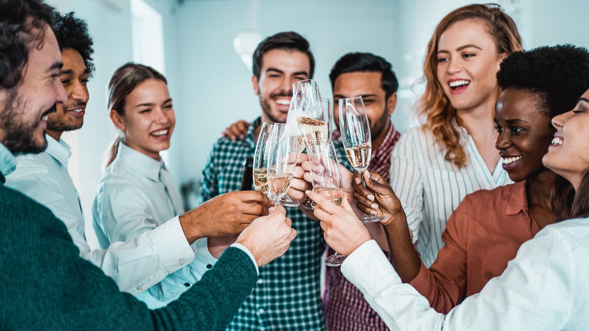 Kollegen feiern in einem Büro. Sie stoßen mit Sekt an.