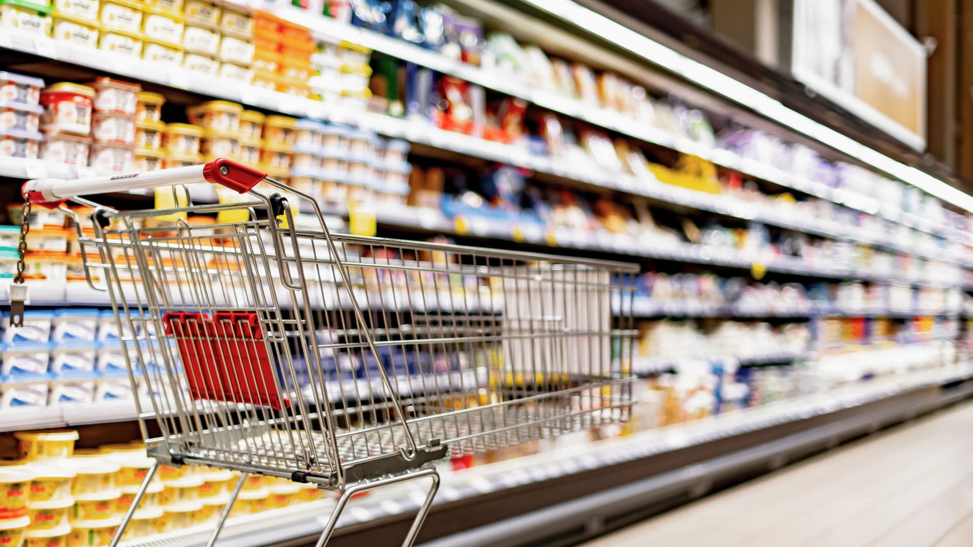 Leerer Einkaufswagen an einem Verkaufsregal in einem Supermarkt