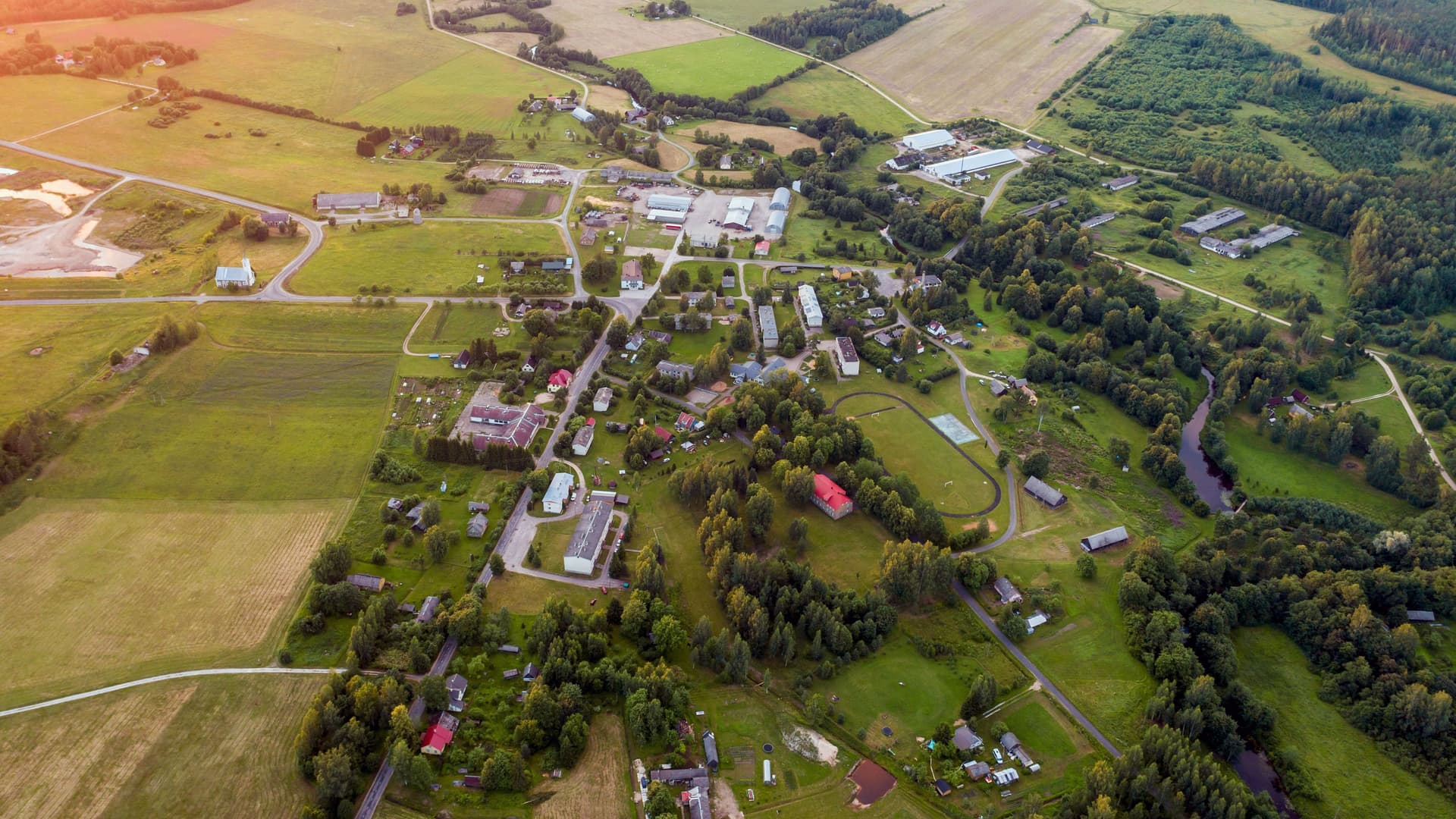 Luftaufnahme einer kleinen Ortschaft umgeben von Feldern und Wald.