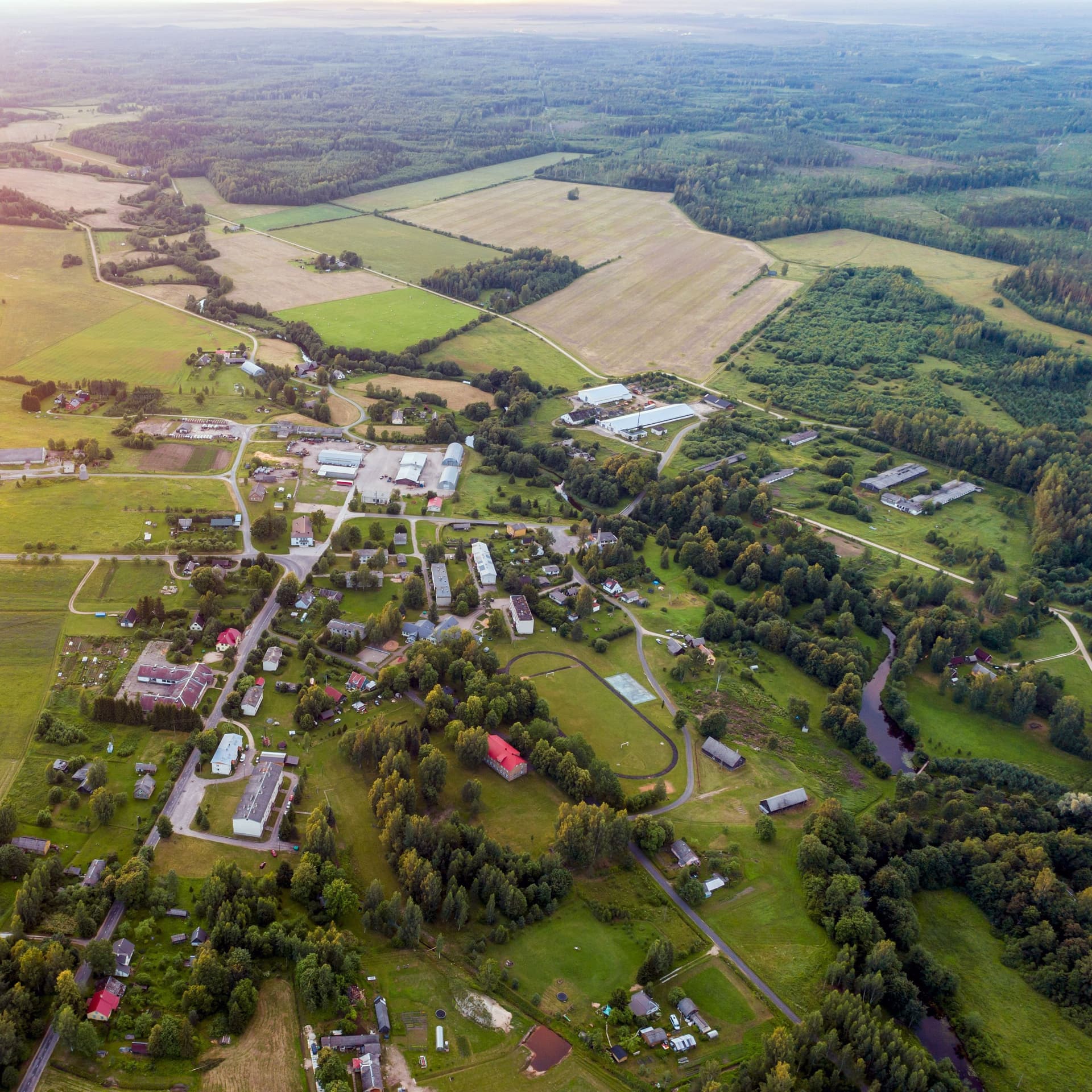 Luftaufnahme einer kleinen Ortschaft umgeben von Feldern und Wald.