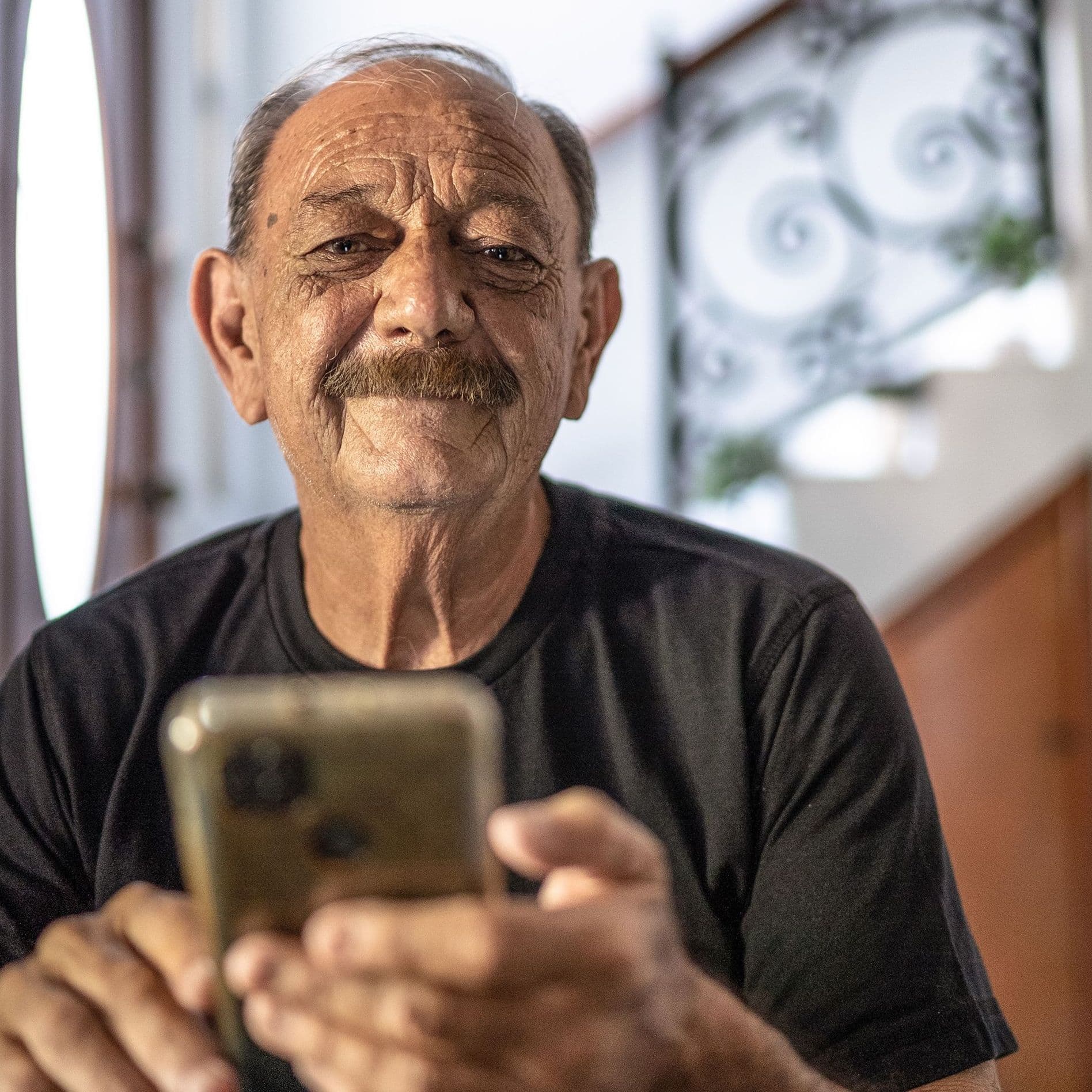 älterer Mann mit Handy innen