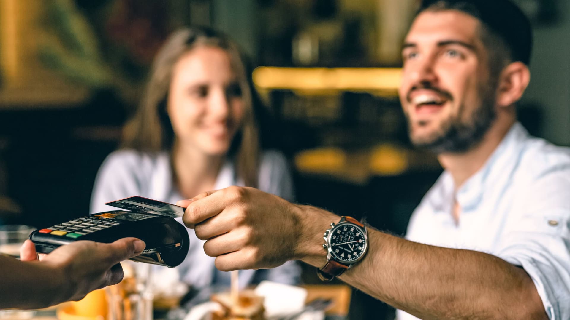 Zufriedener Mann zahlt im Restaurant kontaktlos mit Karte.