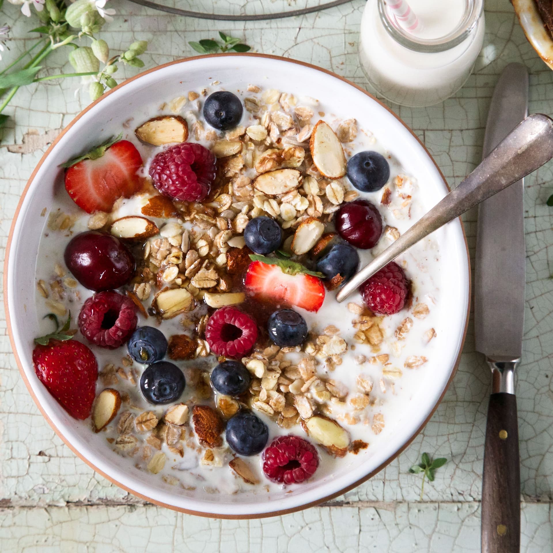 Müsli mit frischen Früchten und Milch in einer Müslischale mit Löffel.