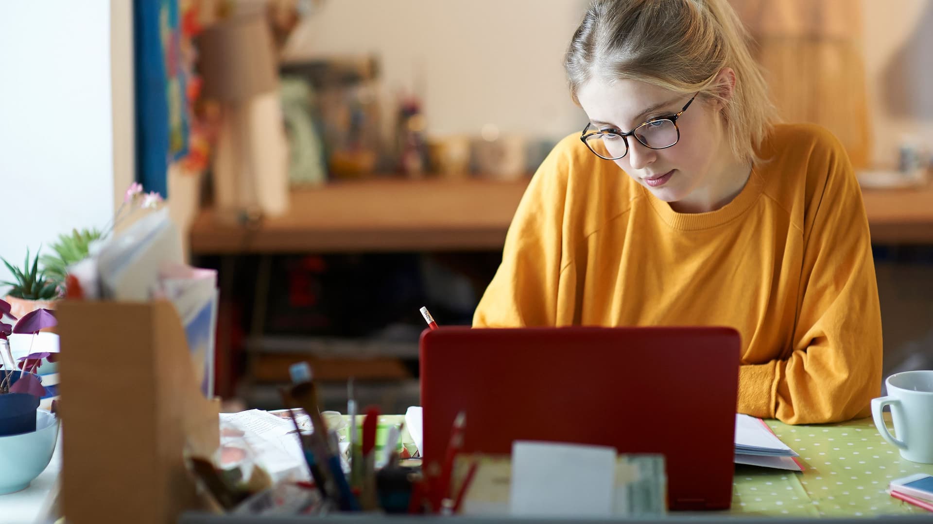 Eine junge Frau lernt zuhause vor ihrem Laptop.
