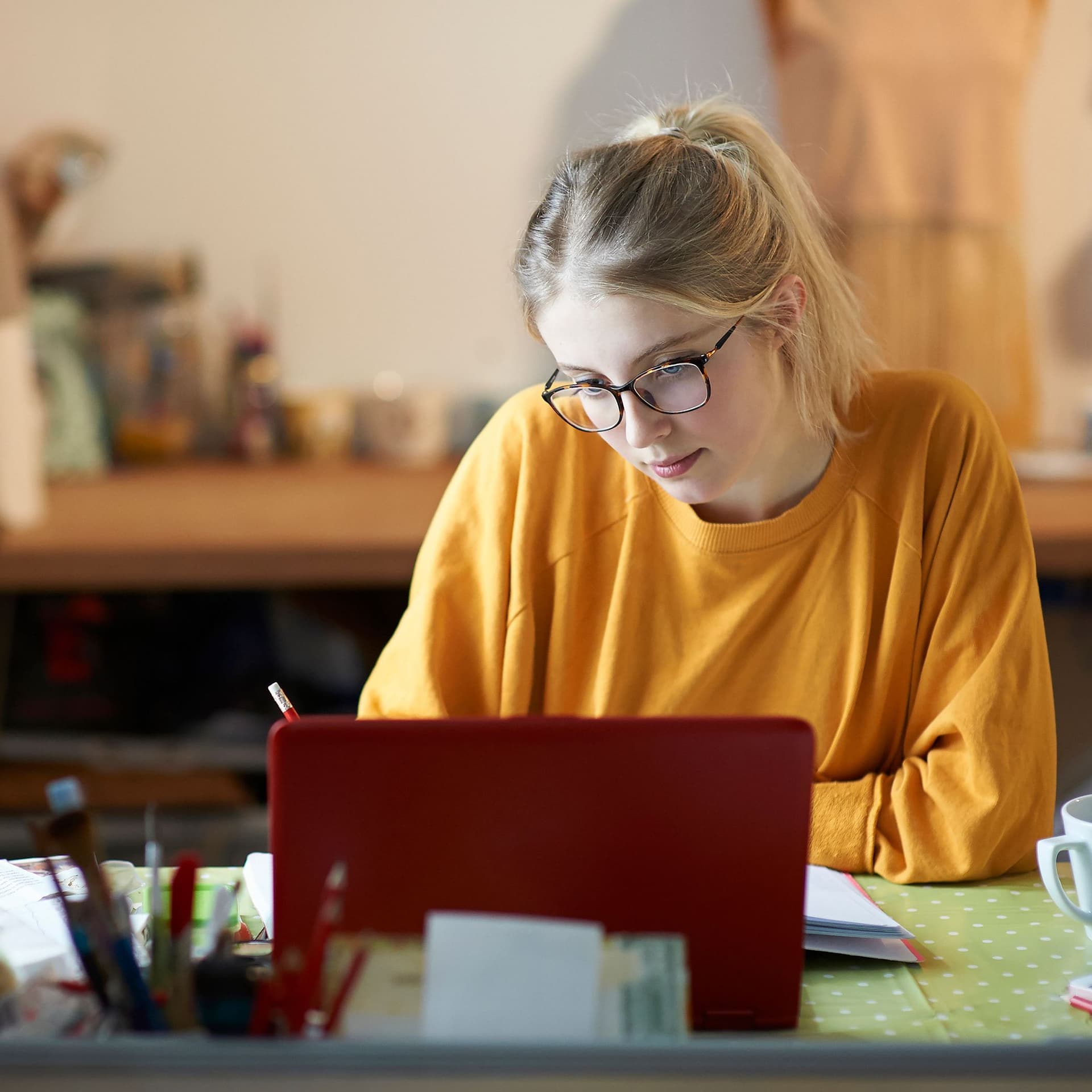 Eine junge Frau lernt zuhause vor ihrem Laptop.