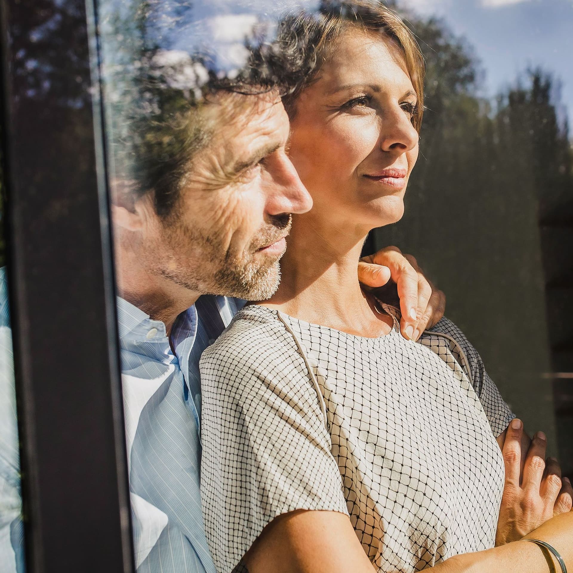 Paar mittleren Alters blickt aus dem Fenster