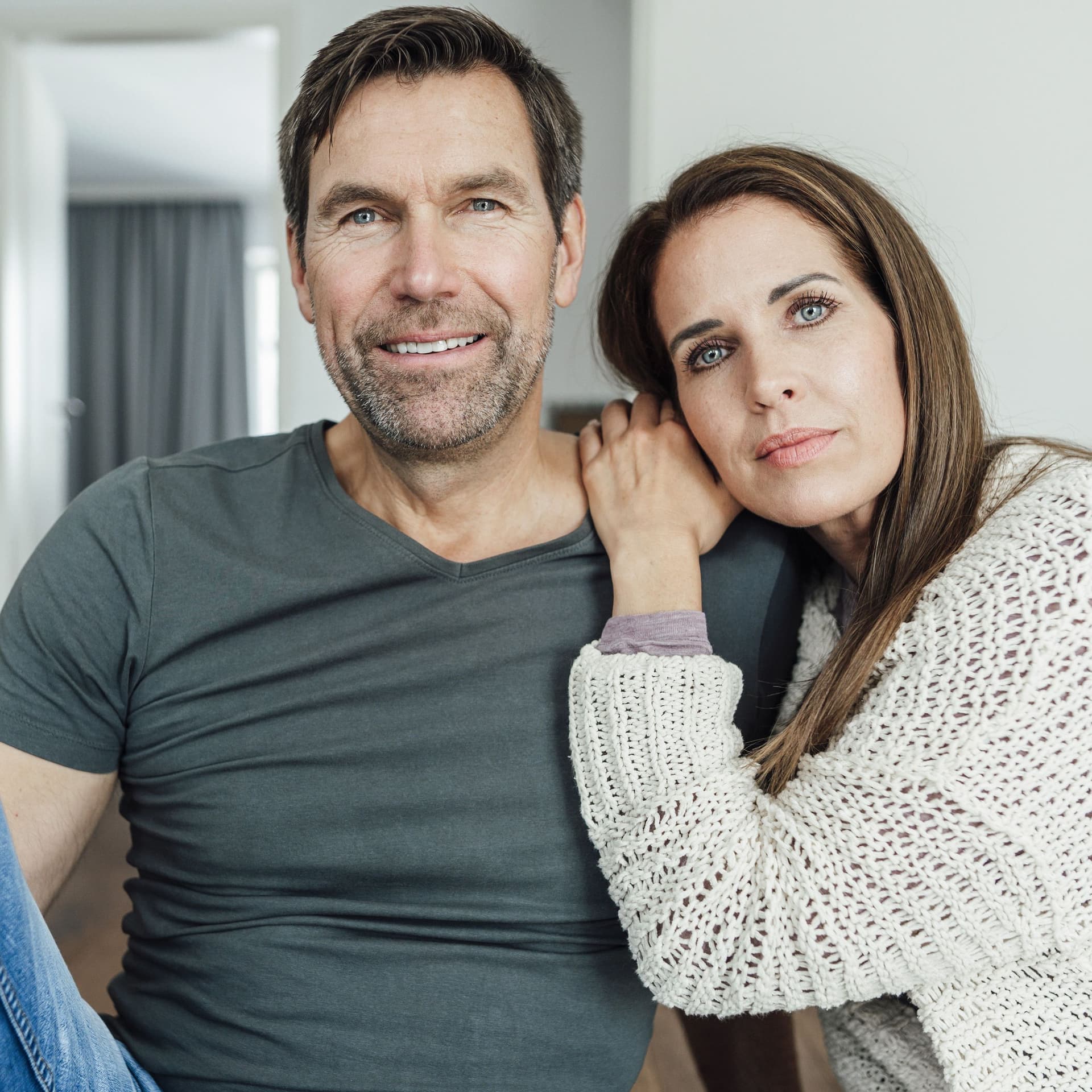 Mann und Frau sitzen zusammen auf einer Couch. Sie lehnt den Kopf an seine Schulter.