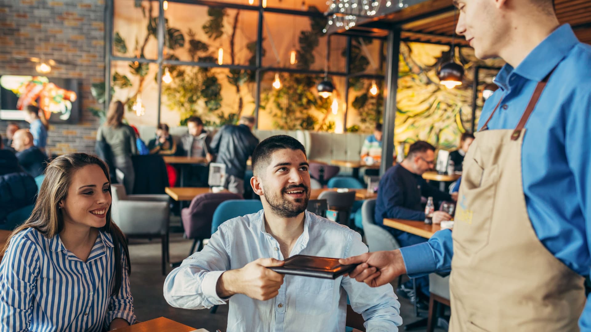 Paar erhält die Restaurantrechnung in einem schwarzen Lederetui.