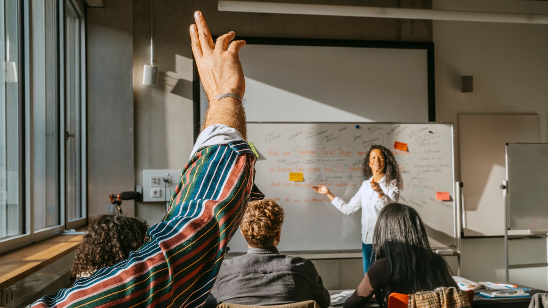 person-meldet-sich-klassenraum-erwachsenenbildung-GI-1374490591