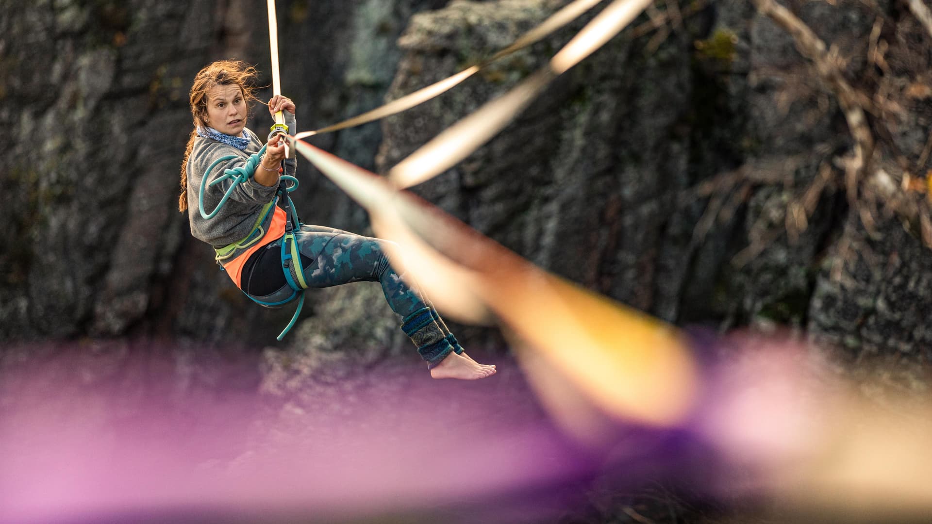 Junge Frau balanciert über Highline die zwischen Felswänden gespannt ist.