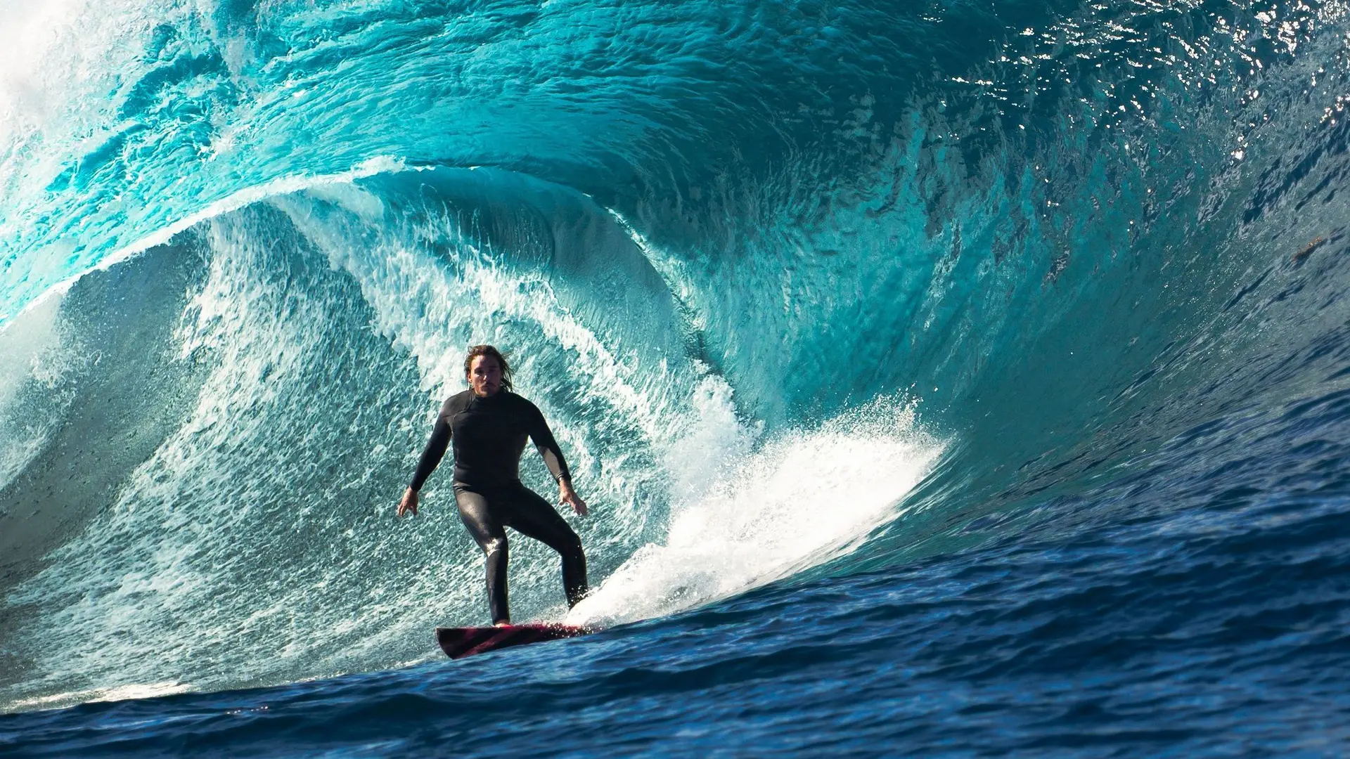Mann auf einem Surfboard inmitten einer Welle.
