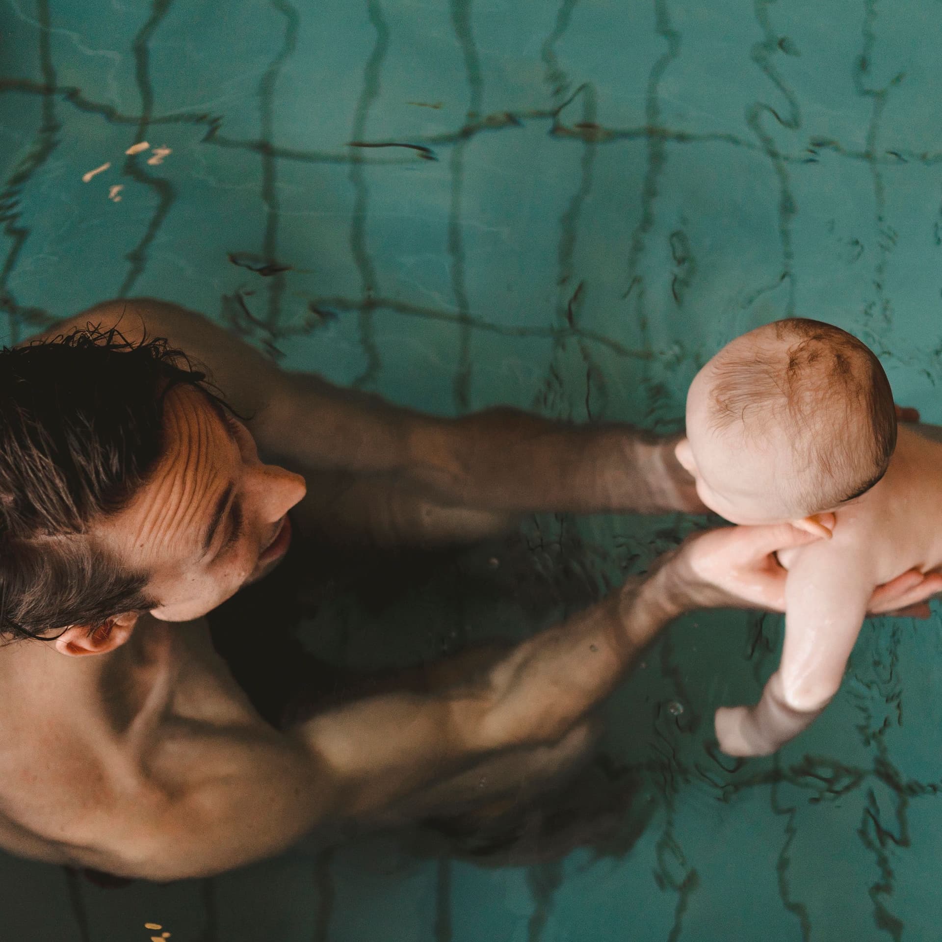 Junger Vater mit Baby in einem Schwimmbecken