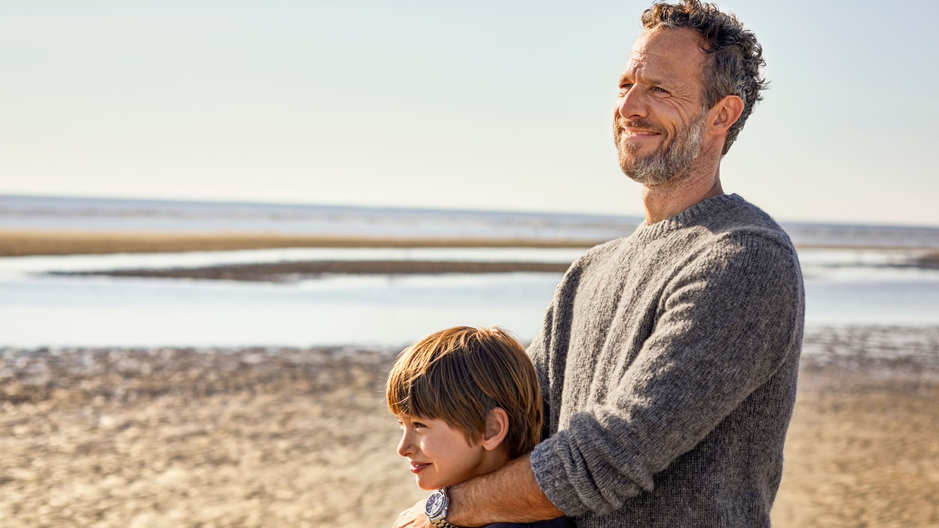 Vater umarmt seinen Sohn am Strand