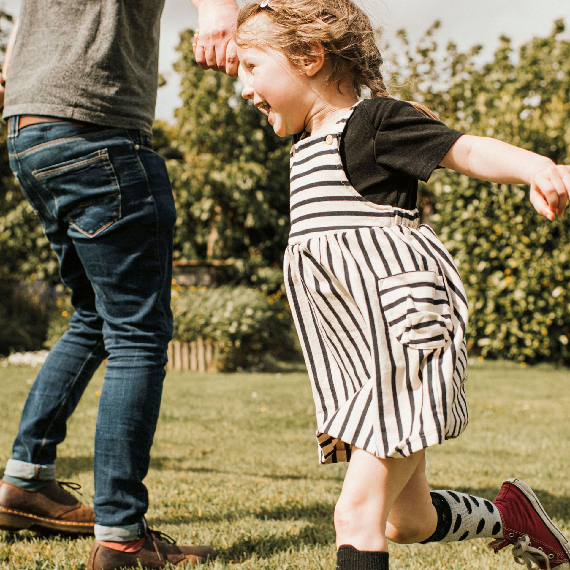 Zwei Kinder toben mit ihrem Vater im Park