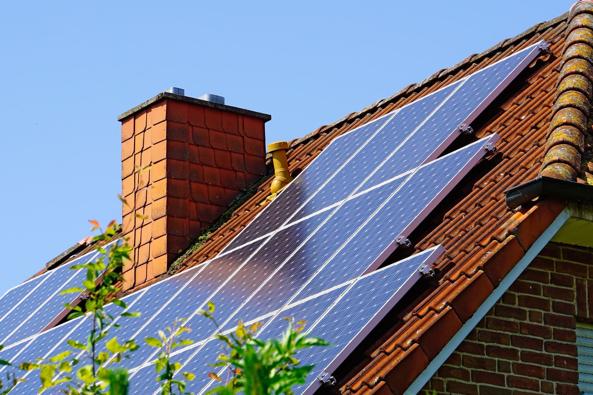 Von einem Einfamilienhaus ist nur das Dach und ein Schornstein zu sehen. Auf der Dachschräge sind eine Vielzahl von Solarpannels zu sehen.