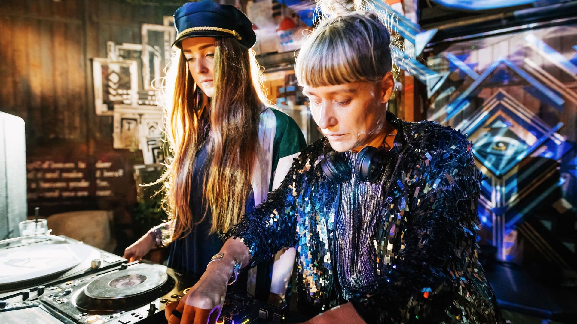Zwei Frauen vor einem DJ-Pult in einem Club.