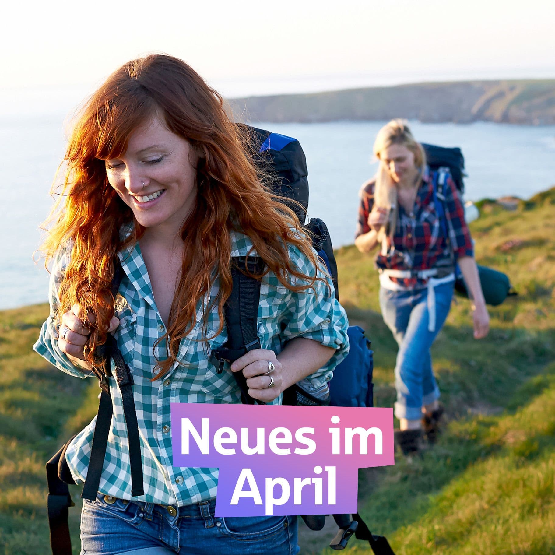 Zwei junge Frauen wandern an der Küste Englands. In der Mitte steht auf einem farbigen Hintergrund "Neues im April"
