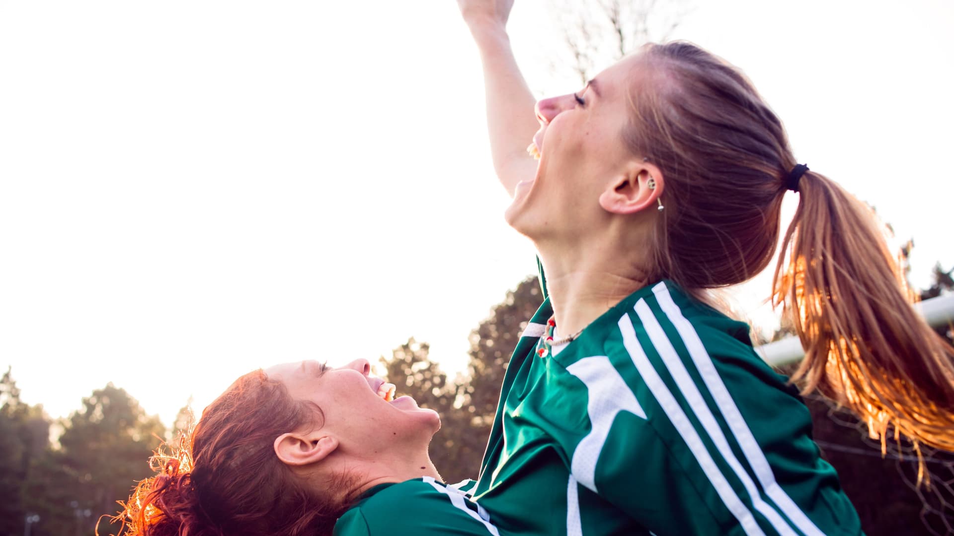 Zwei Frauen in Sportanzug umarmen sich feierlich.