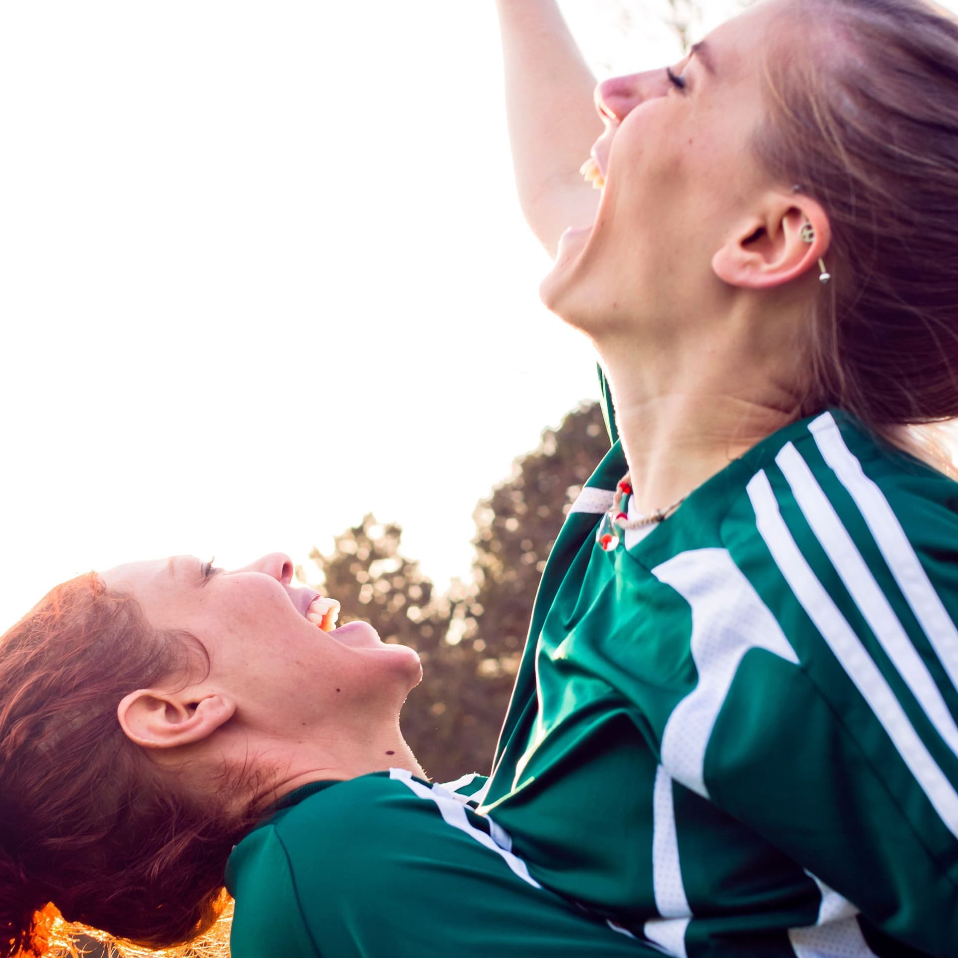 Zwei Frauen in Sportanzug umarmen sich feierlich.