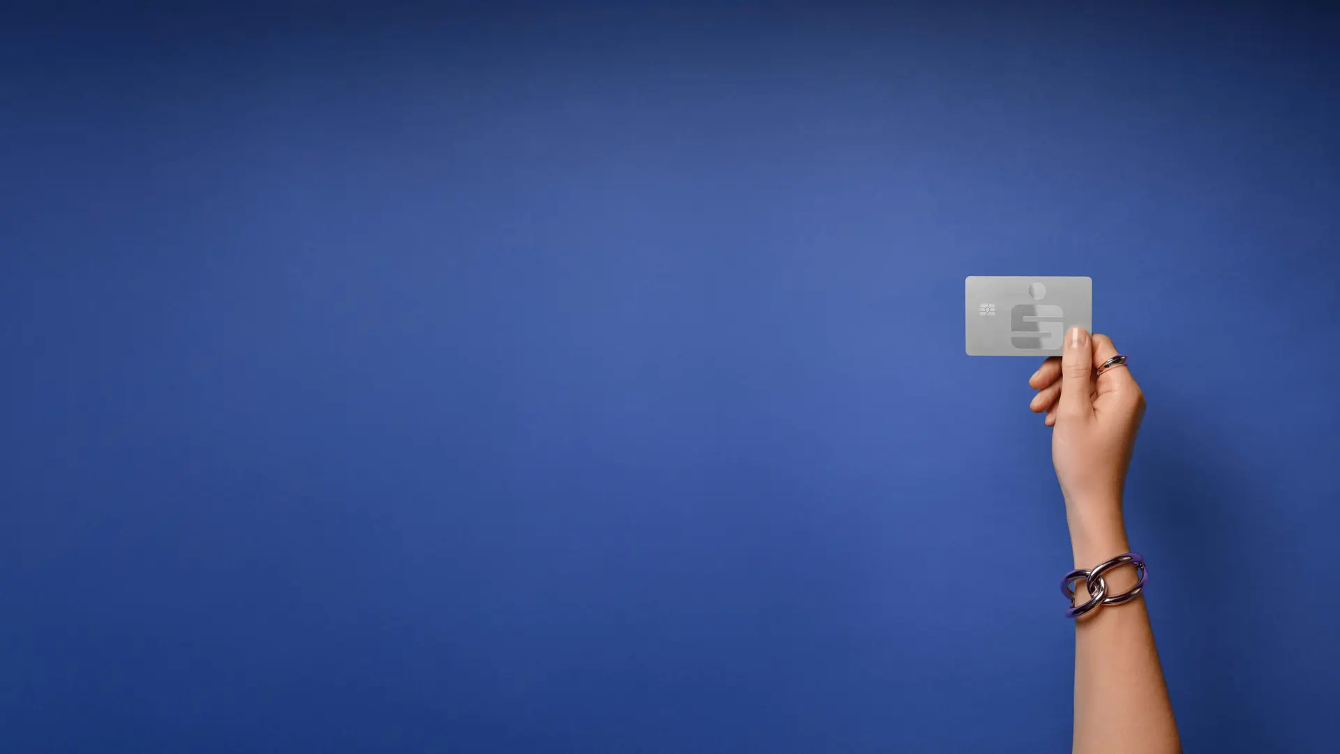 Hand hält eine silberne Sparkassen-Kreditkarte vor blauem Hintergrund