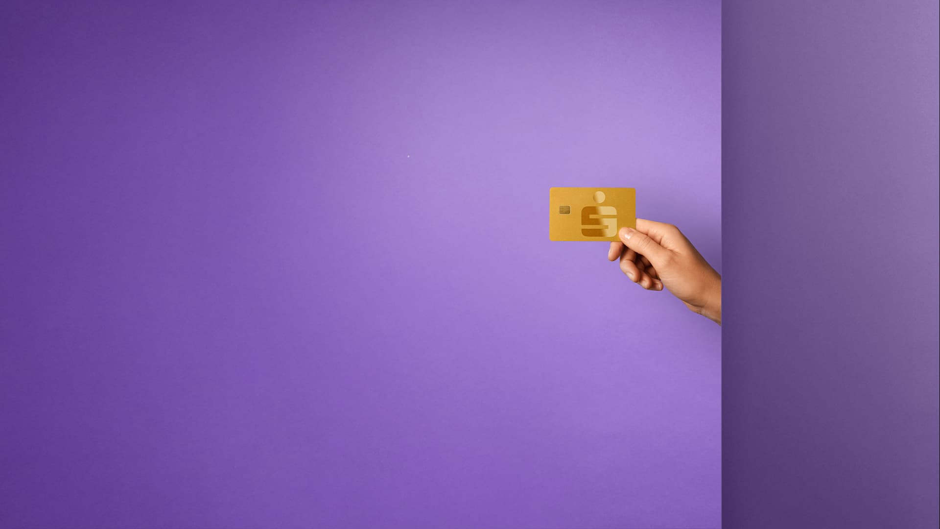 Eine Hand hält eine goldene Sparkassen-Karte vor violettem Hintergrund.