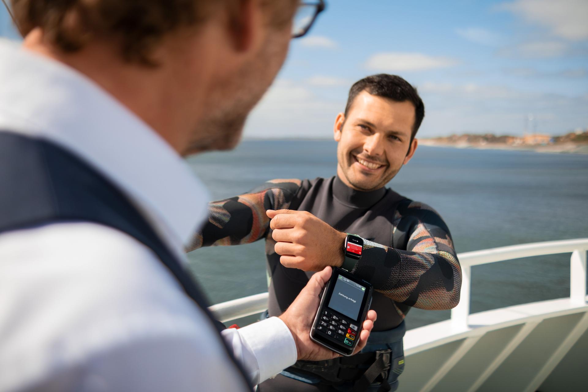 Ein Mann bezahlt auf einem Schiff mit seiner Apple-Watch