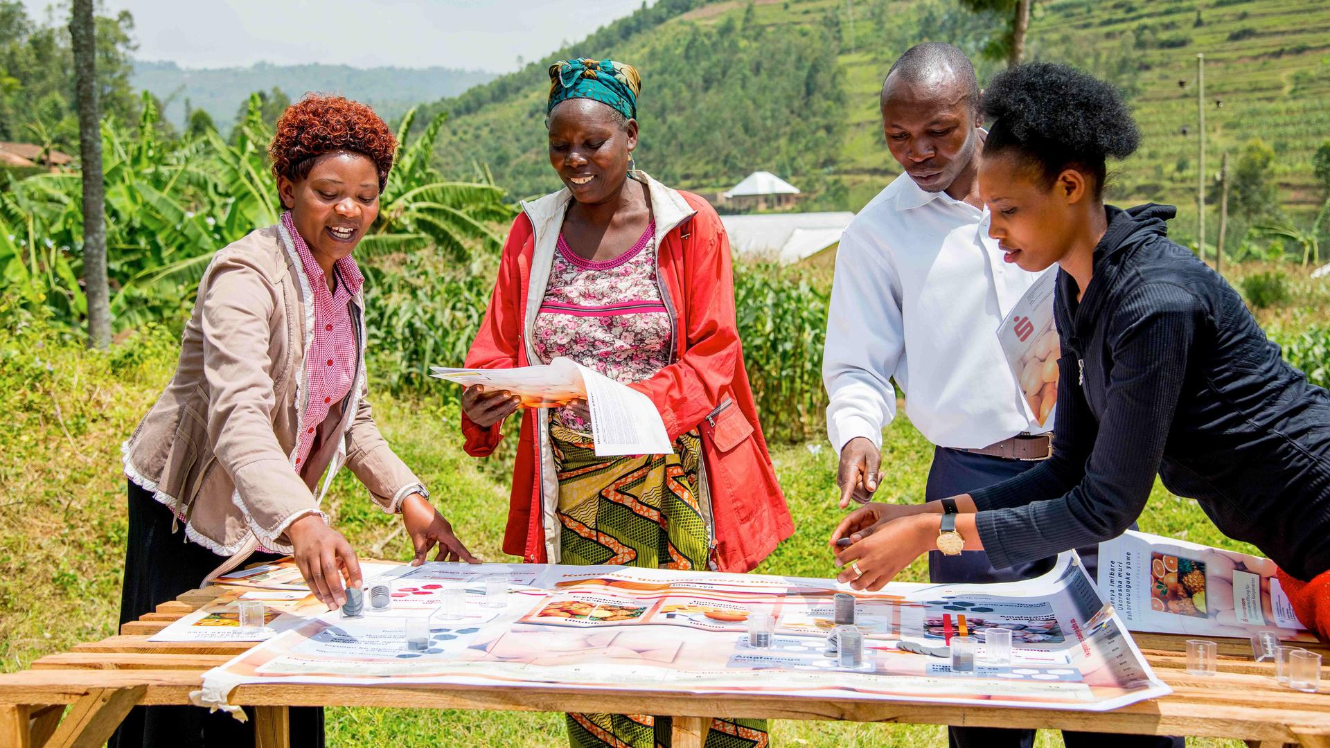 Menschen in Ruanda stehen um einen Tisch und beraten sich bei einem Unternehmensspiel