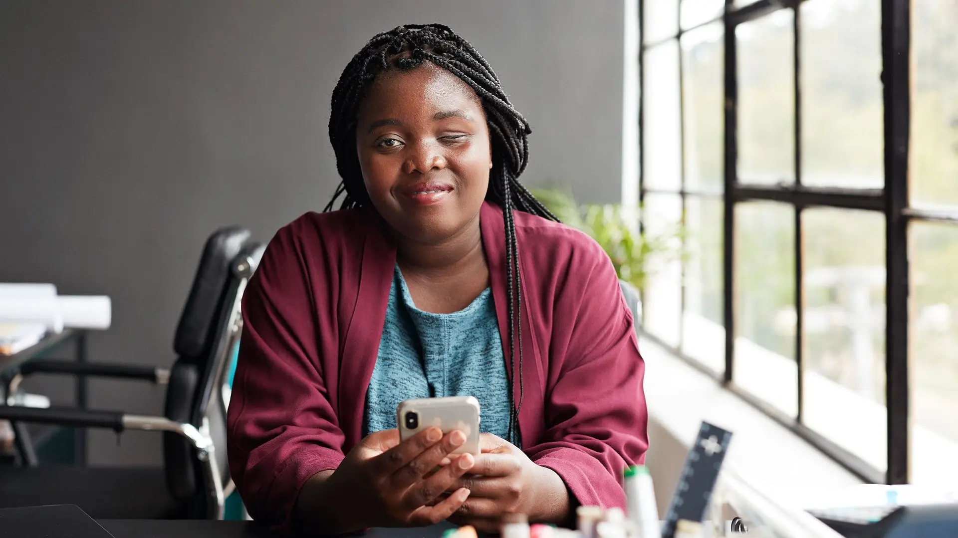 Frau mit Sehbehinderung und Handy am Schreibtisch
