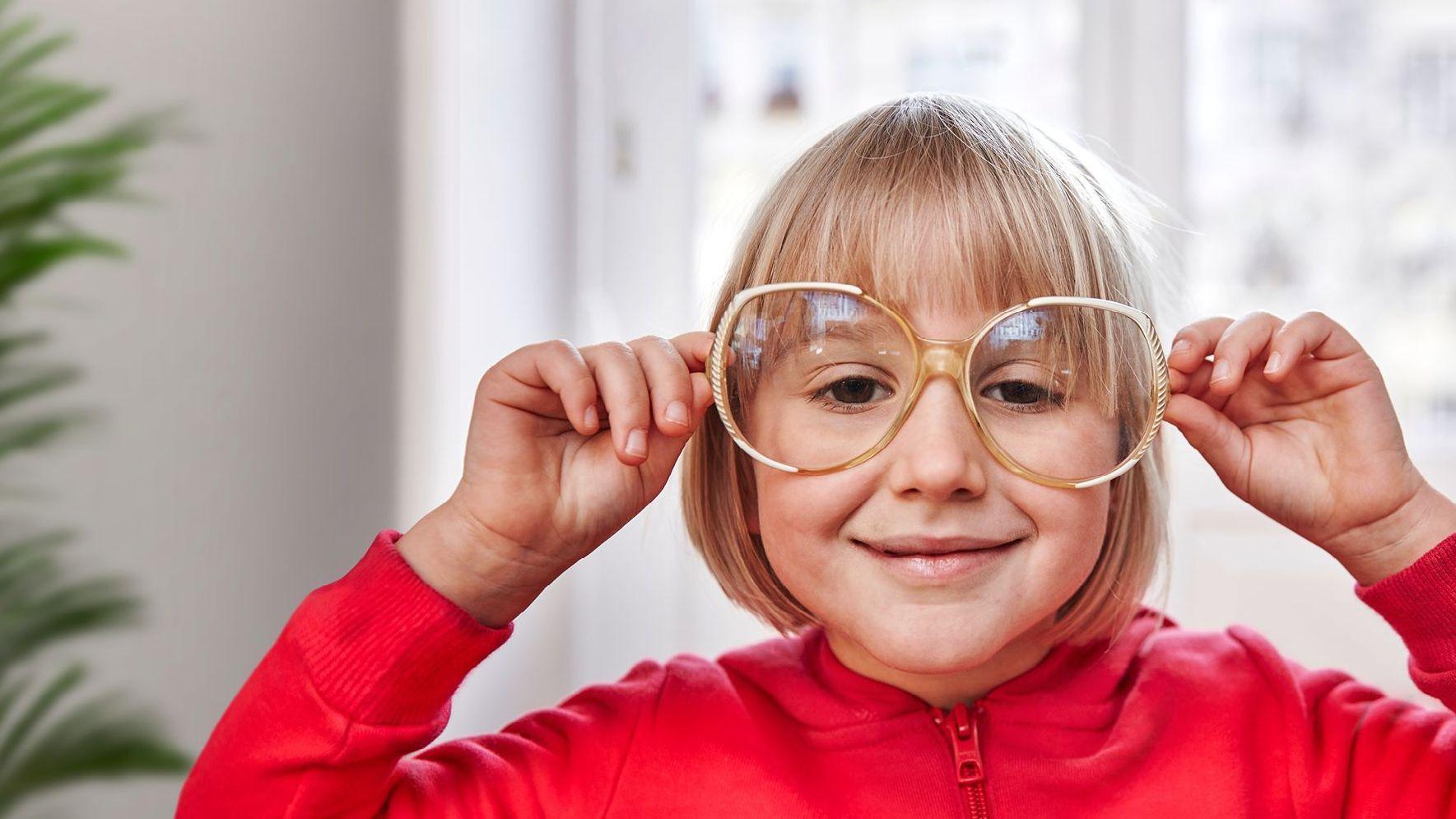 Ein Mädchen schaut durch eine große Brille.