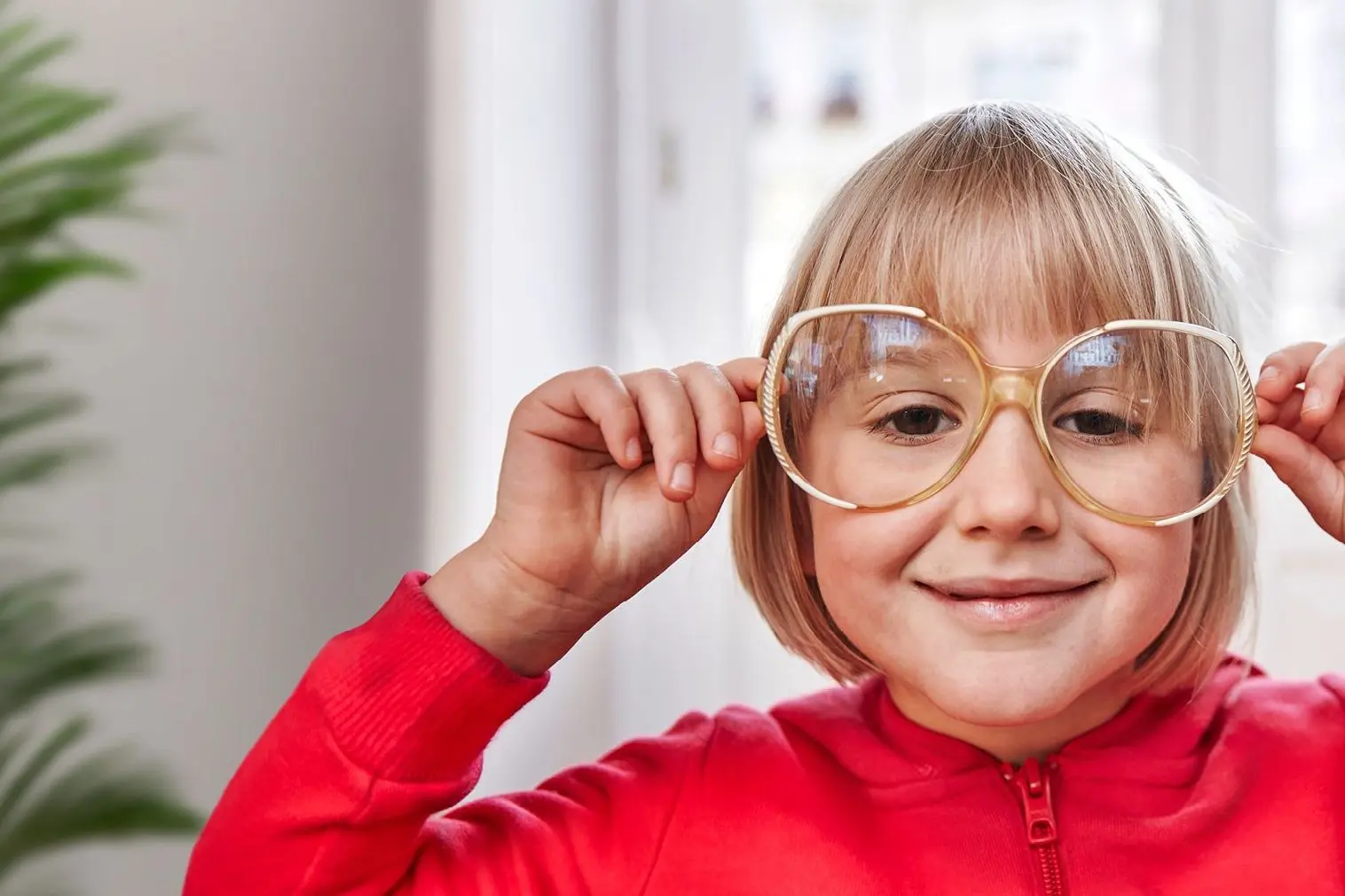 Ein Mädchen schaut durch eine große Brille.