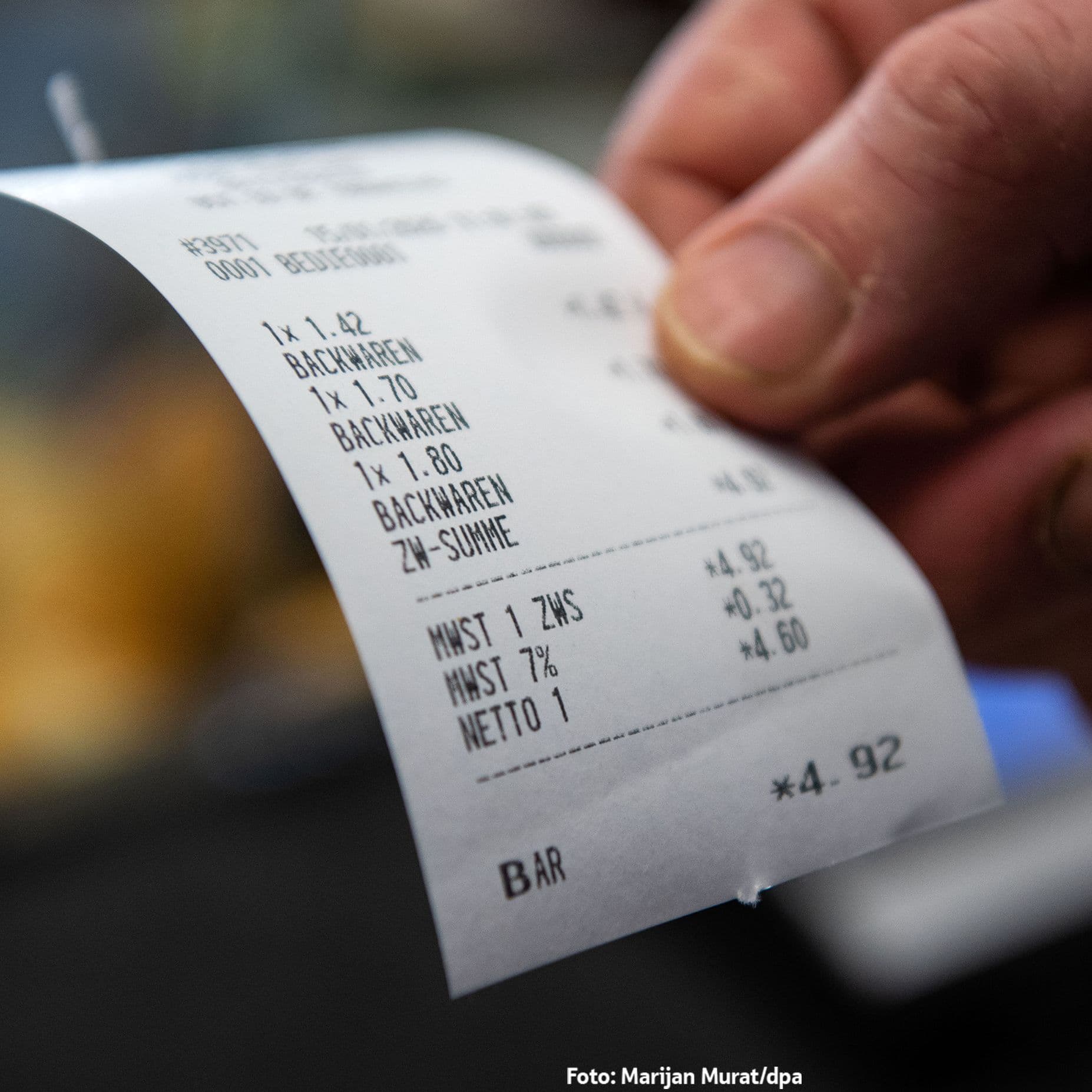 Eine Hand hält einen gedruckten Kassenbon einer Bäckerei über drei Backwaren mit einer Gesamtsumme von 4,92 Euro, bar bezahlt.