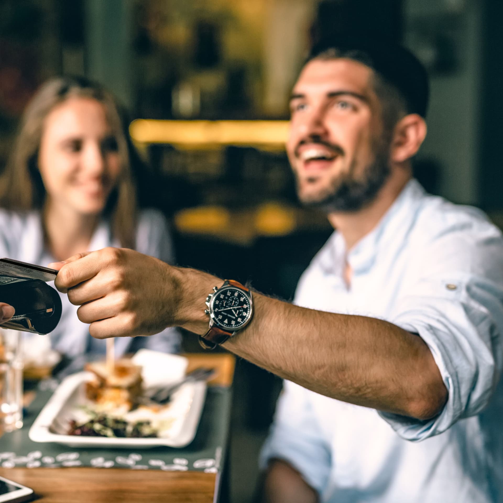 Zufriedener Mann zahlt im Restaurant kontaktlos mit Karte.