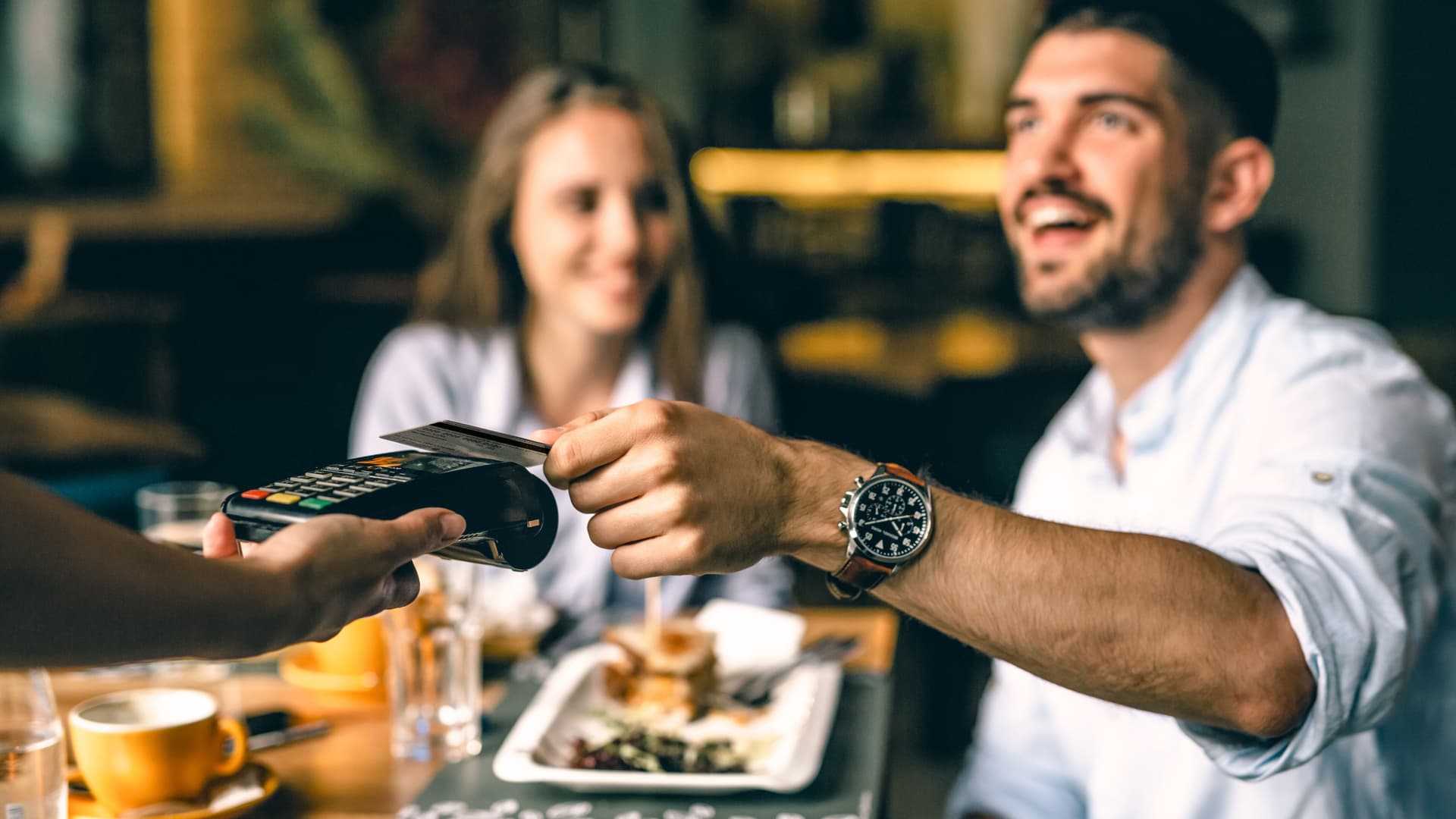 Zufriedener Mann zahlt im Restaurant kontaktlos mit Karte.