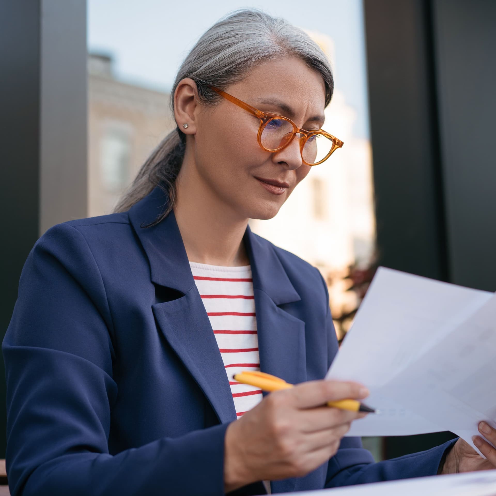 Ältere Frau amLaptop schaut sich Papiere an.