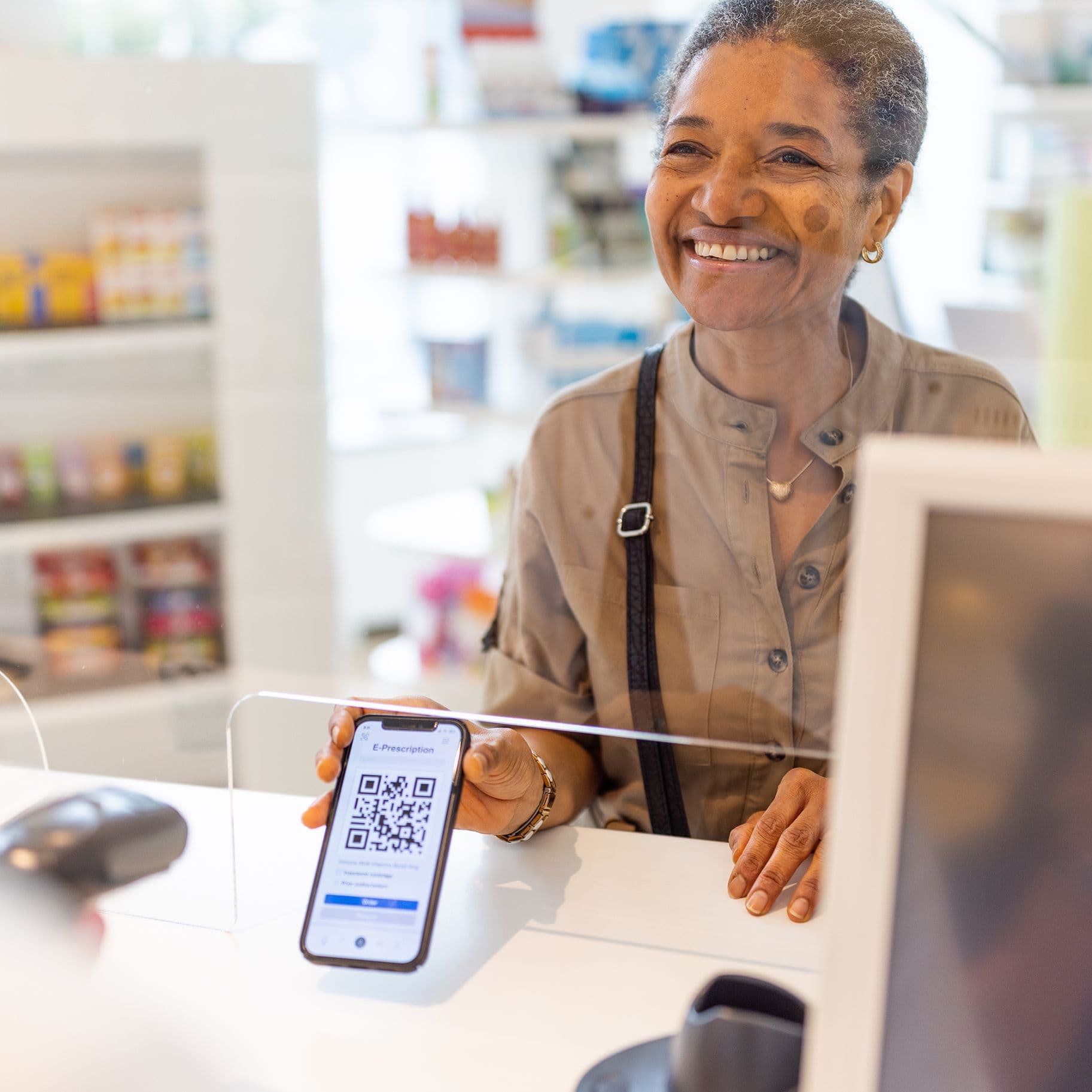 Eine aeltere POC zeigt ihr Handy in einer Apotheke.