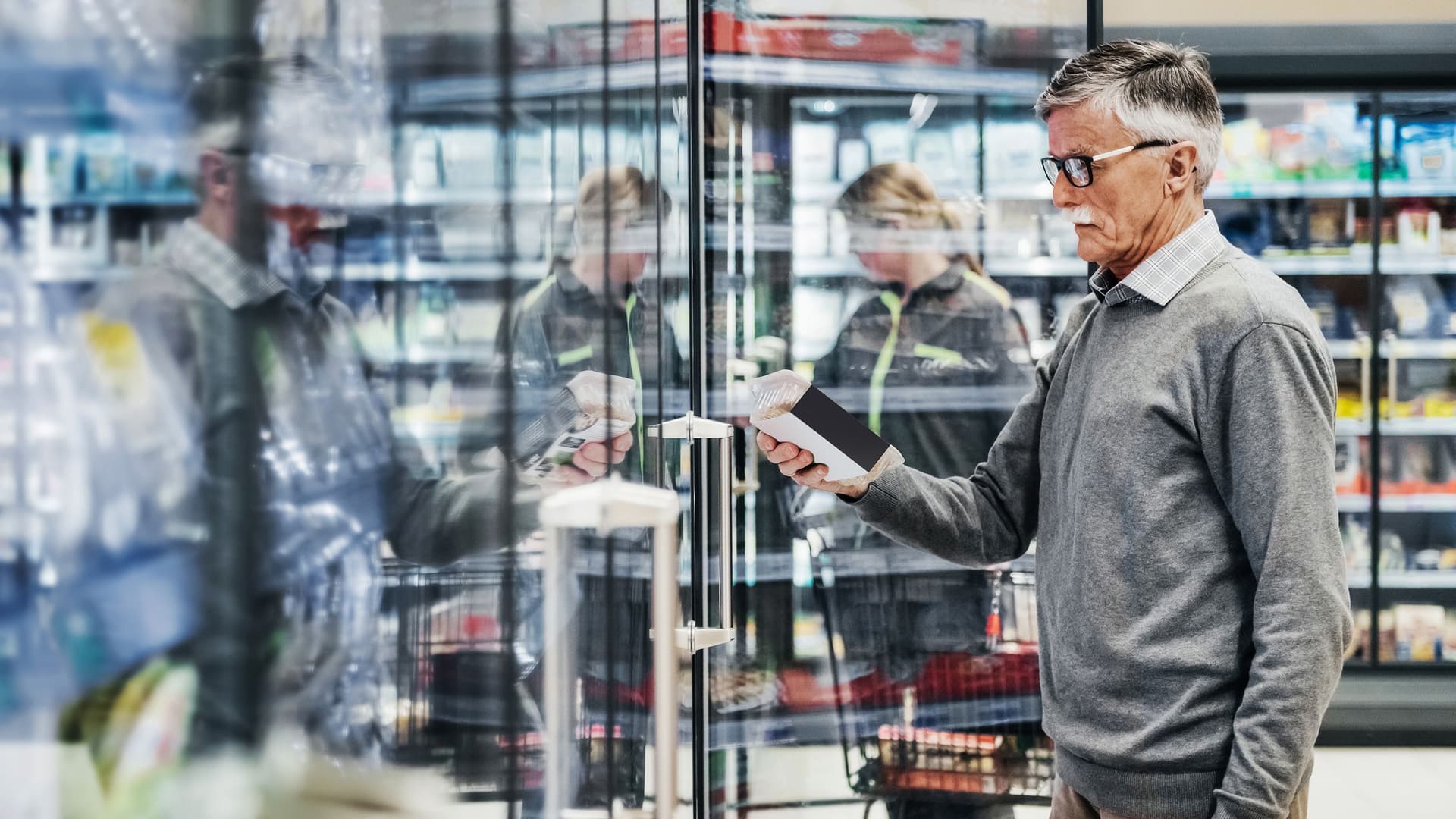 Älterer Mann in Supermarkt checkt Produkte