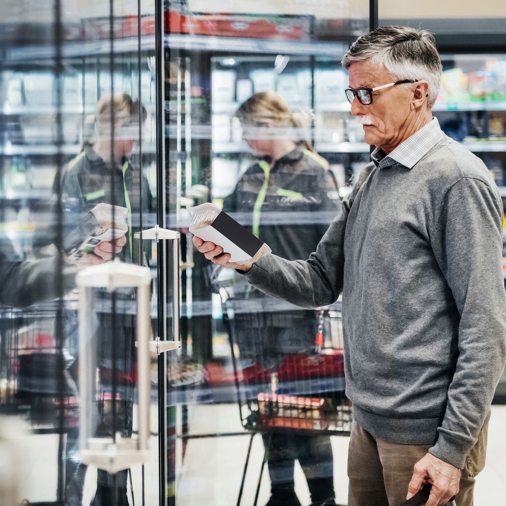 Älterer Mann in Supermarkt checkt Produkte