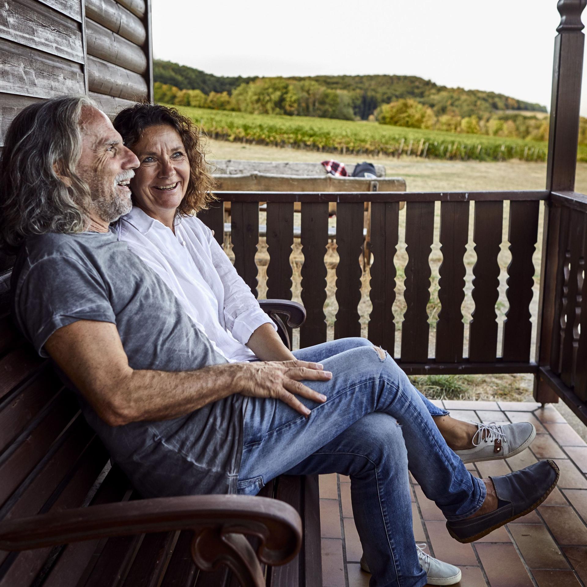 Glückliches reifes Paar, das auf der Veranda einer Blockhütte sitzt
