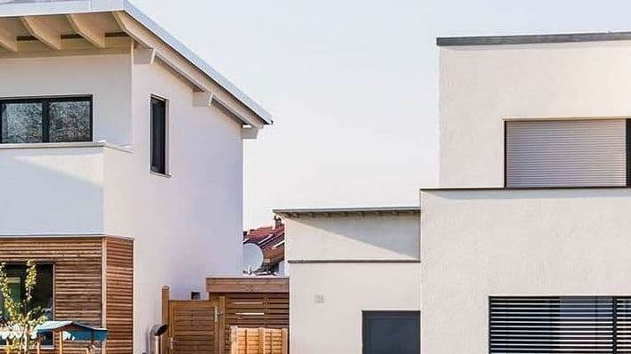 Mehrere Stadtvillen in einer Neubausiedlung mit einer Rasenfläche im Vordergrund.